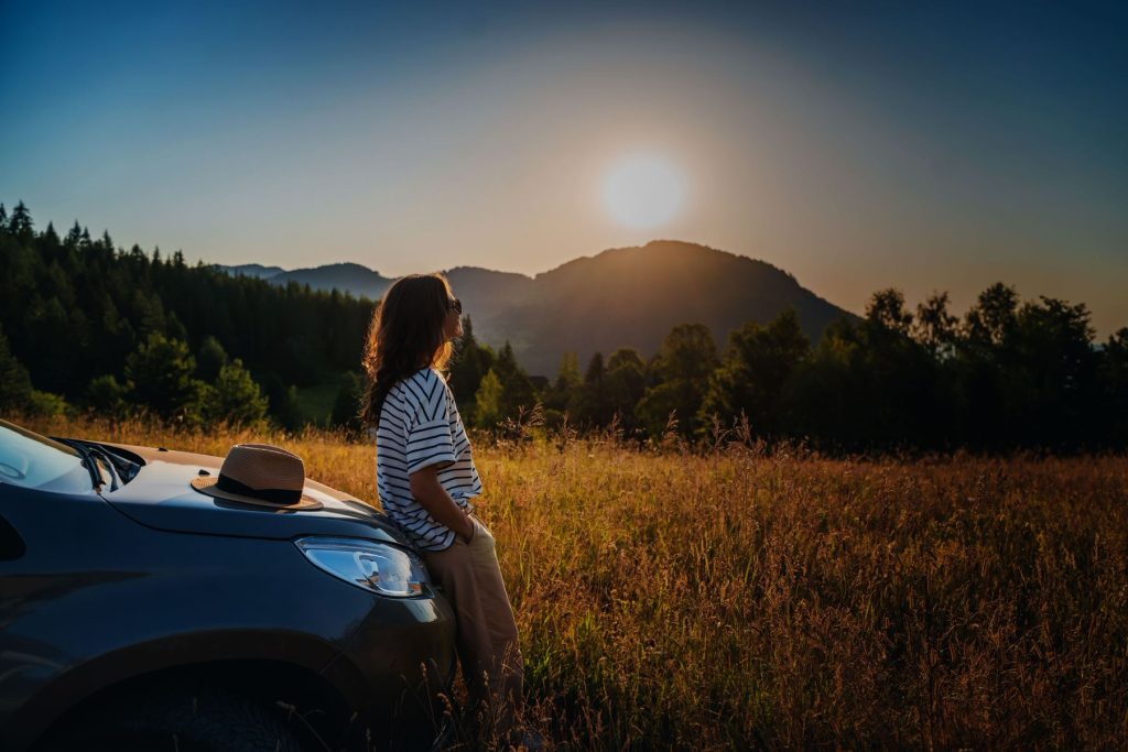 woman leaning on car looking at mountain