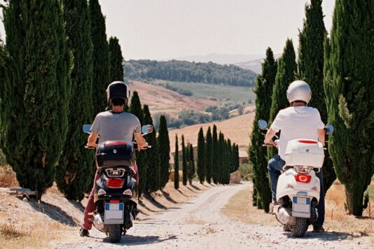 Two people on mopeds during their traveler journey