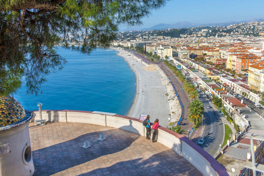 Two tourist looking over a city and beach view of Nice, France